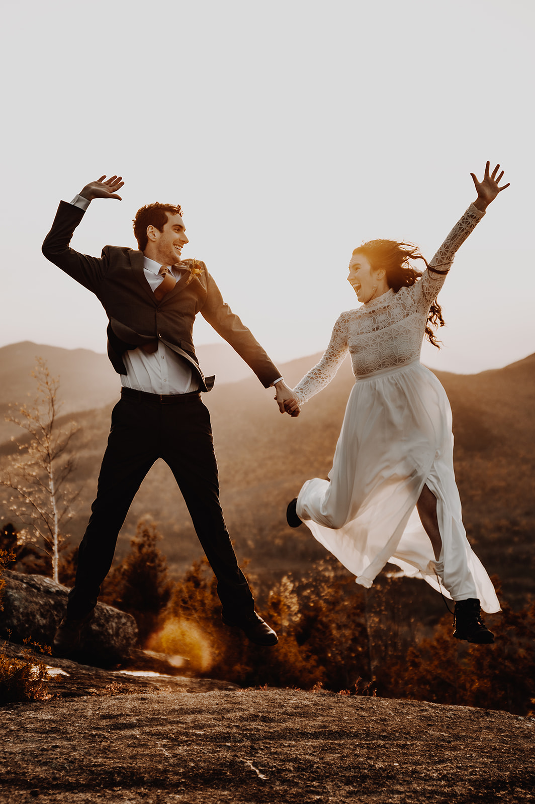 Bride and groom jumping after eloping on a mountain in Lake Placid, NY