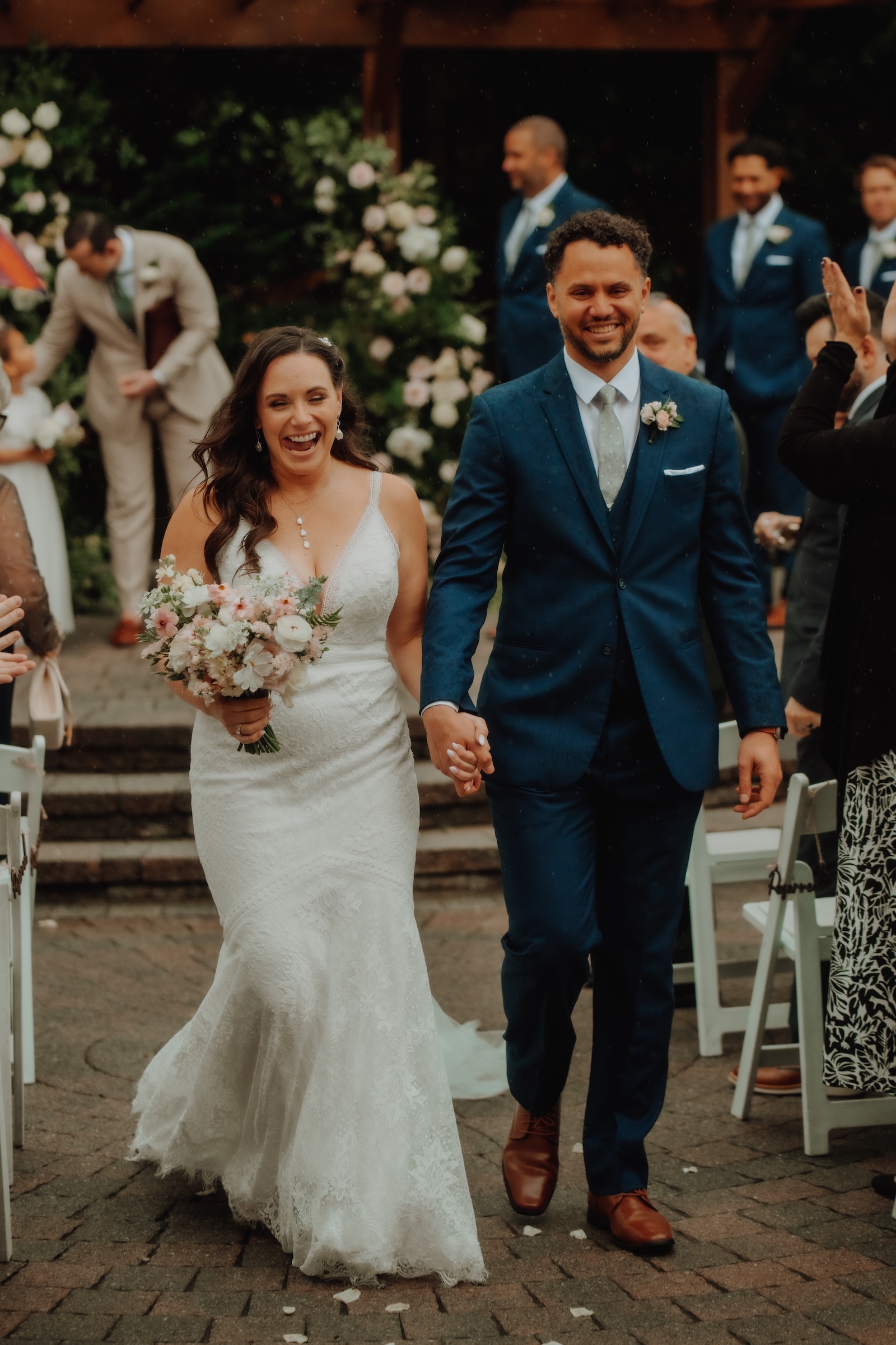 Bride and groom halfway down the aisle following their ceremony at Bear Creek, laughing as the rain picks up